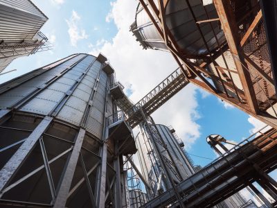 Agricultural Silos. Building Exterior. Storage and drying of grains, wheat, corn, soy, sunflower against the blue sky with white clouds.